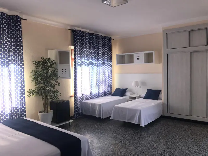 Une chambre lumineuse avec deux lits simples et un décor sobre.