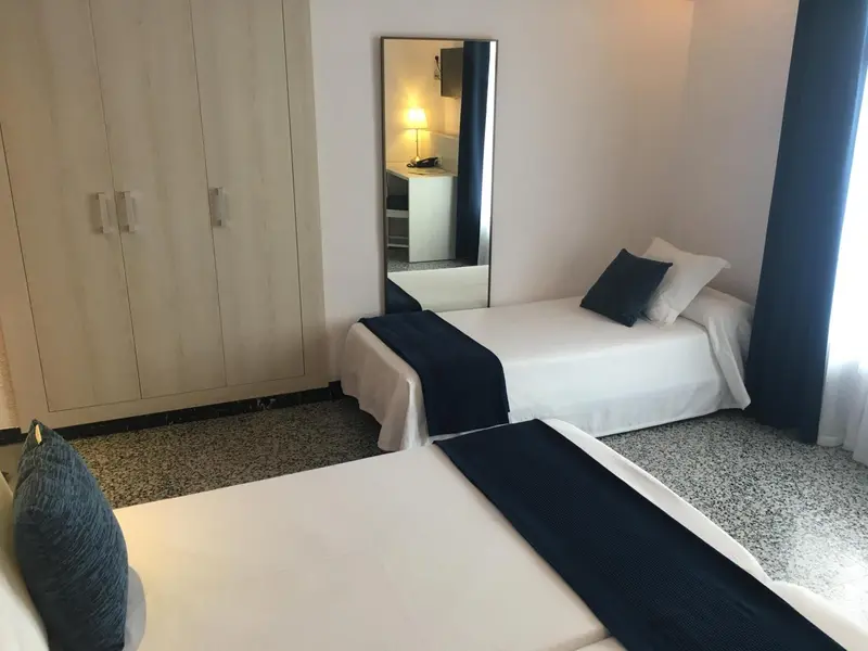 Une chambre lumineuse avec deux lits simples et un grand miroir.