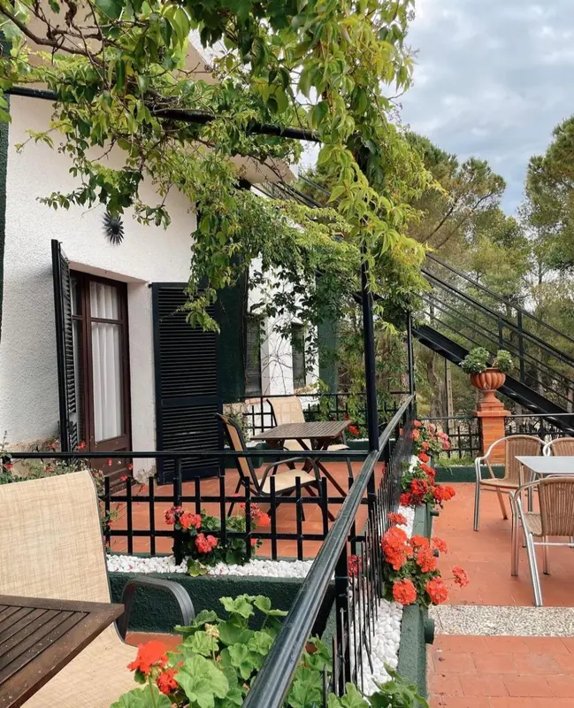 Terrasse fleurie avec mobilier de jardin devant un bâtiment blanc.