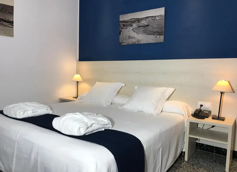 Une chambre lumineuse avec un grand lit recouvert d'une courtepointe blanche et de serviettes.