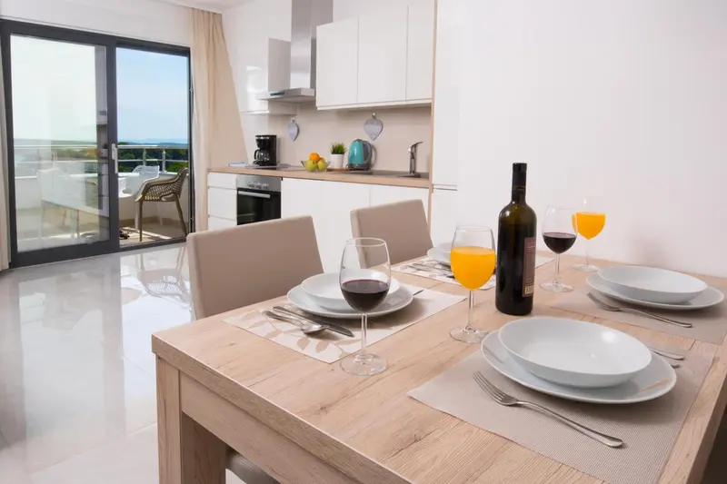 Une table est dressée dans une cuisine lumineuse avec vue sur l'extérieur.