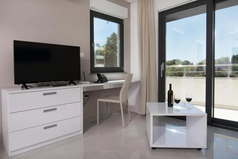 Une chambre lumineuse avec un bureau et une bouteille de vin sur une table basse.