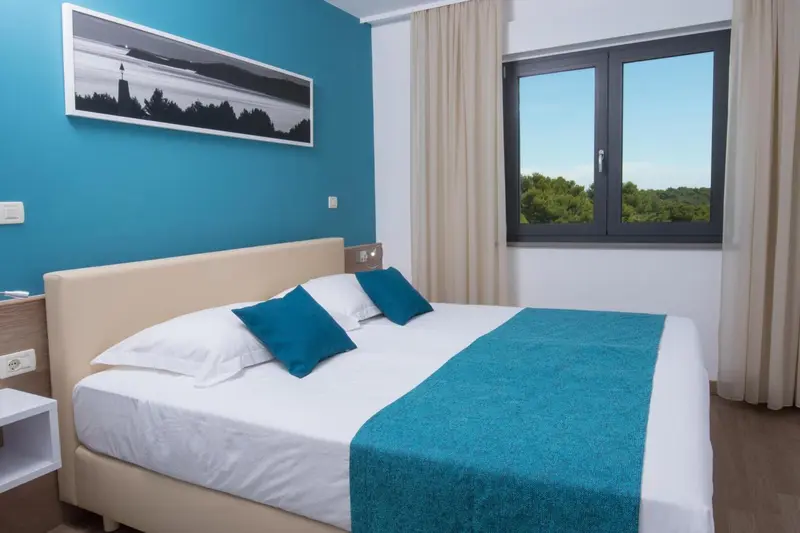 Une chambre lumineuse avec un grand lit et une décoration turquoise.