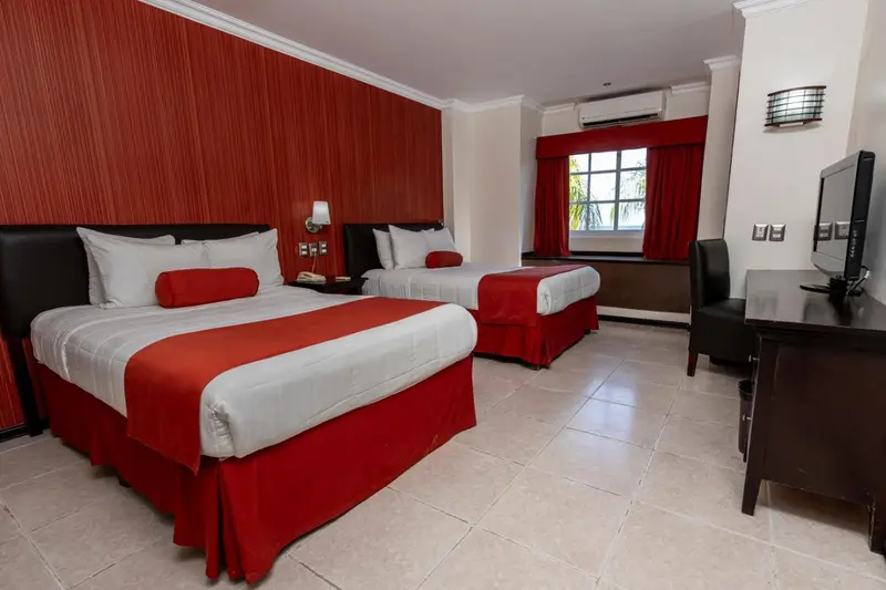 Deux lits simples avec une couverture rouge dans une chambre lumineuse.