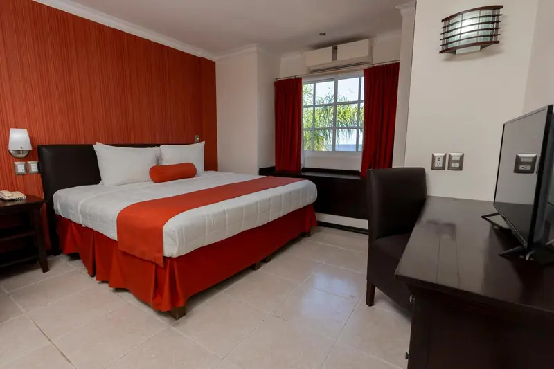 Une chambre d'hôtel avec un grand lit recouvert d'une courtepointe rouge et d'oreillers blancs.