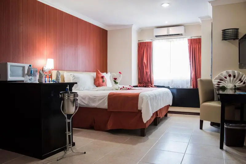 Une chambre d'hôtel avec un lit décoré de pétales de roses et une petite table.