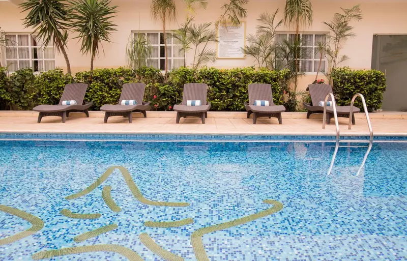 Transats alignés au bord d'une piscine carrelée.