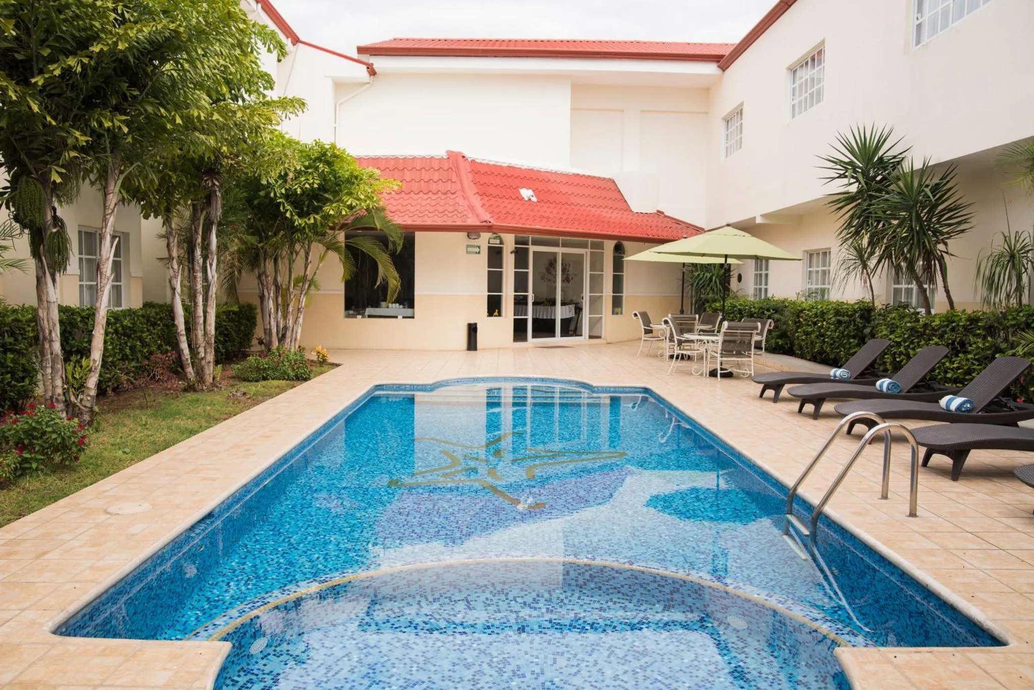 Une piscine rectangulaire avec des transats et une végétation luxuriante.