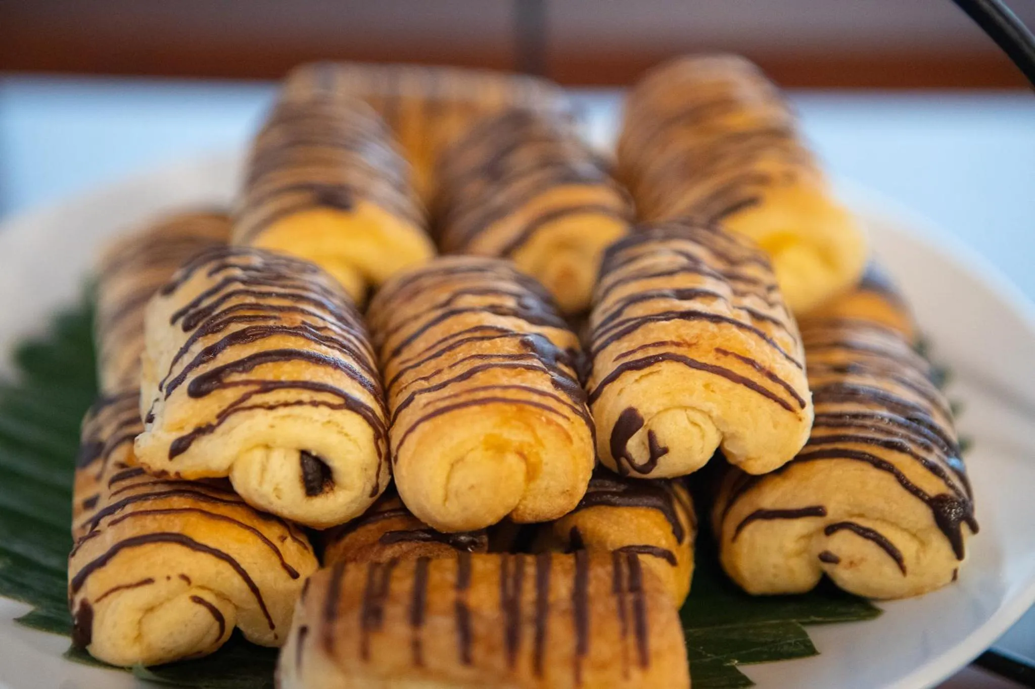 Assortiment de viennoiseries enroulées et nappées de chocolat sur une assiette.