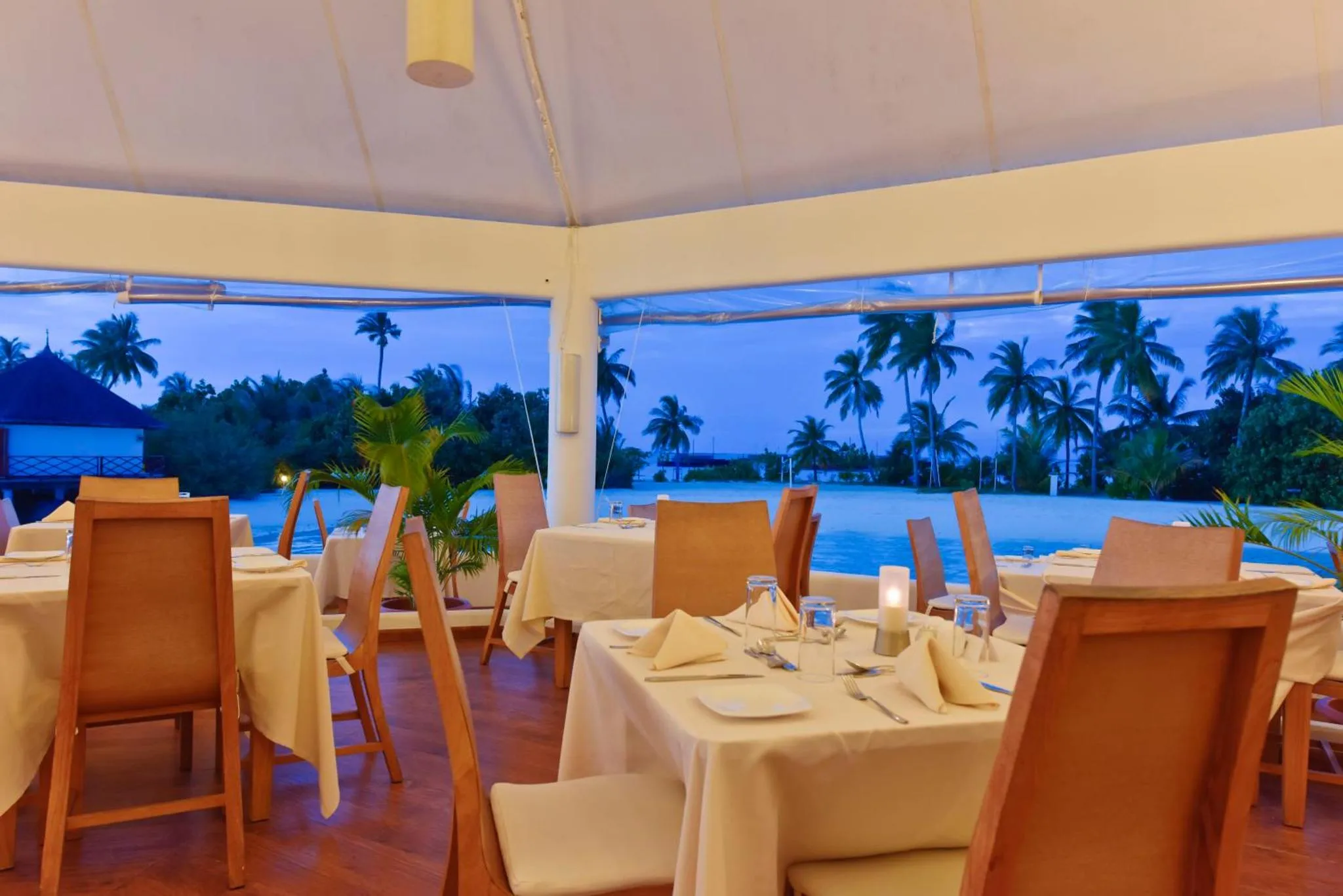 Une salle à manger lumineuse avec des tables dressées face à l'océan.