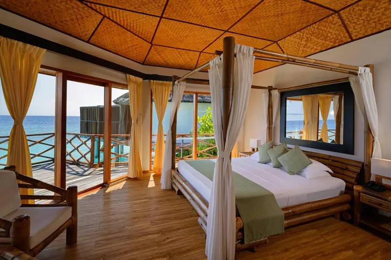 Une chambre lumineuse avec un lit à baldaquin donnant sur l'océan.
