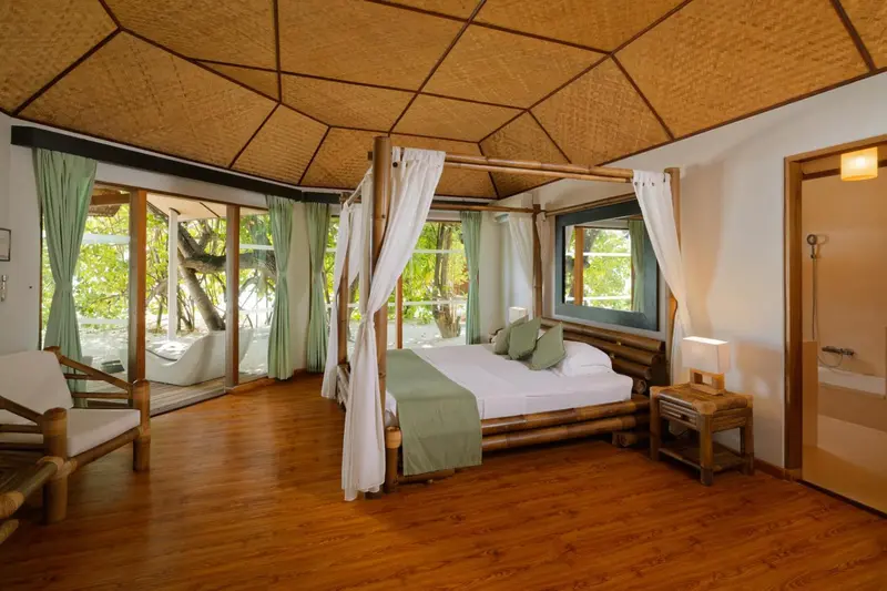 Une chambre avec un lit à baldaquin donnant sur une plage.