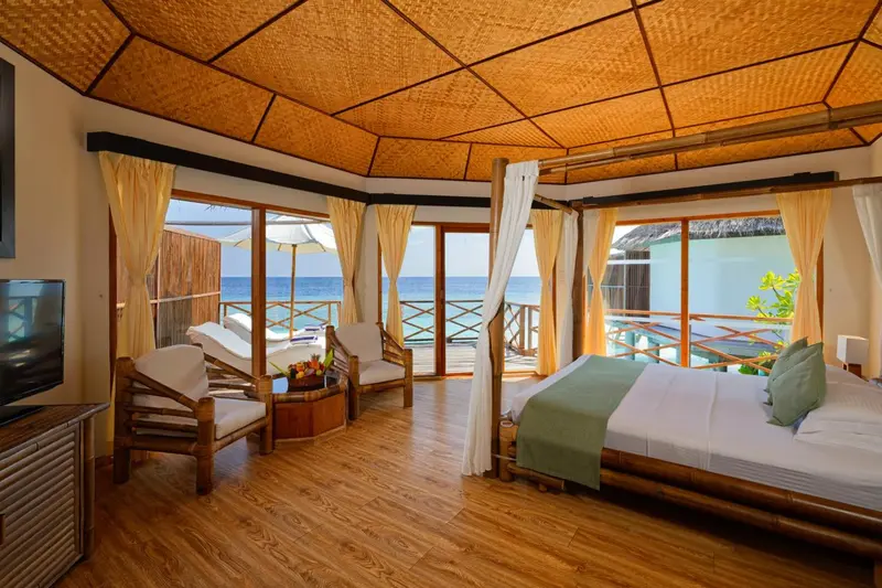 Chambre lumineuse avec lit à baldaquin donnant sur une plage.