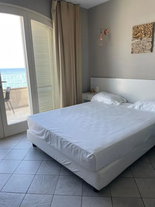 Une chambre lumineuse avec un grand lit blanc et une vue sur la mer.
