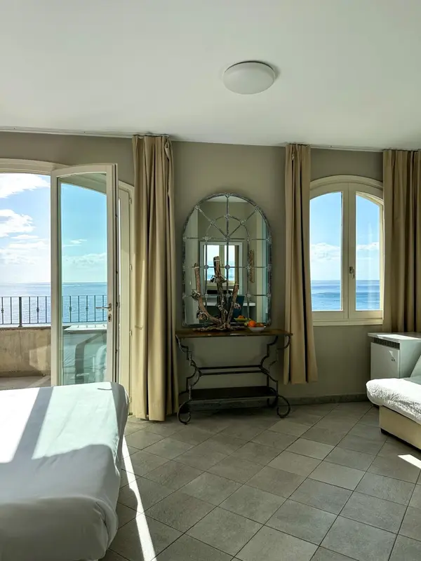 Une chambre lumineuse avec vue sur la mer par de grandes fenêtres.