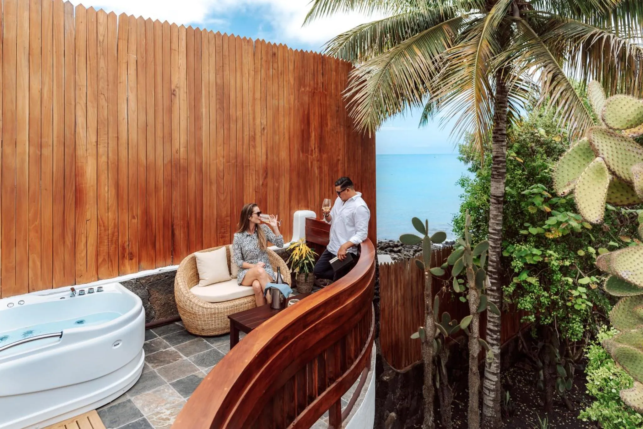 Un couple discute sur une terrasse avec jacuzzi face à la mer.