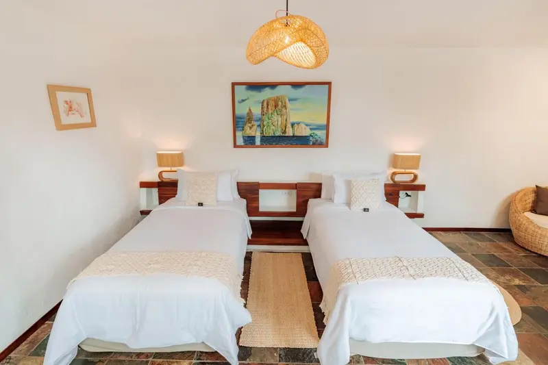 Une chambre lumineuse avec deux lits simples et une décoration murale.