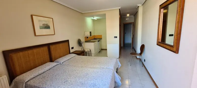 Une chambre lumineuse avec un lit et un coin cuisine.