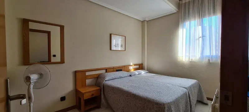 Une chambre lumineuse avec un lit double et un miroir mural.