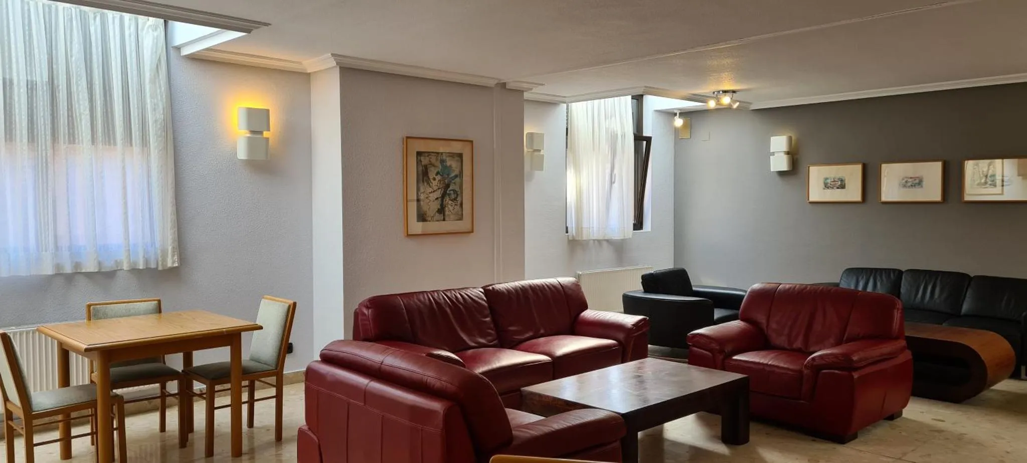 Un espace de séjour avec canapés et une table à manger près d'une fenêtre.