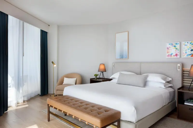 Une chambre lumineuse avec un grand lit et un fauteuil.