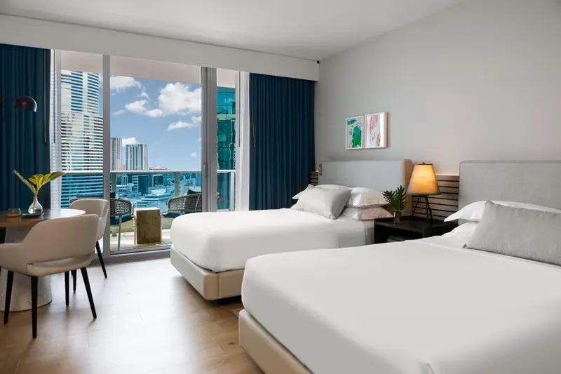 Chambre lumineuse avec deux lits et vue sur la mer.