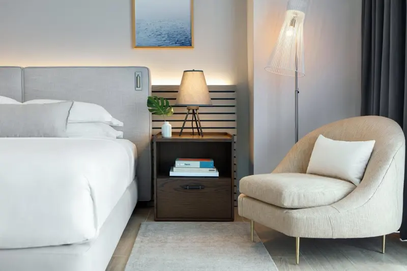 Une chambre lumineuse avec un grand lit et un fauteuil confortable.