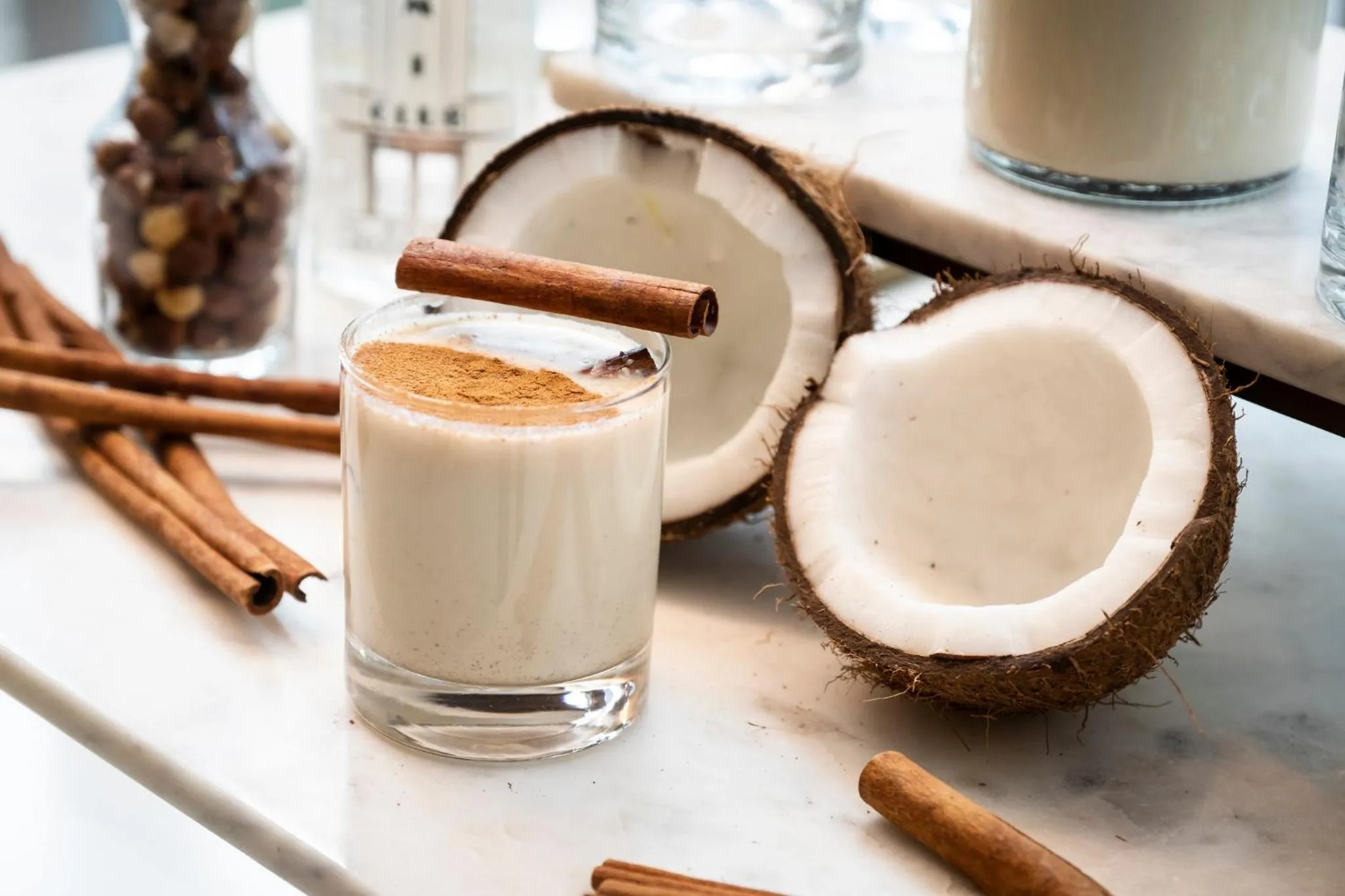 Boissons crémeuses et noix de coco fraîches sur une surface claire.