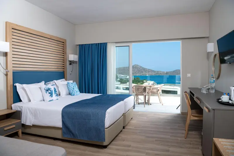 Chambre lumineuse avec un grand lit donnant sur une vue mer.