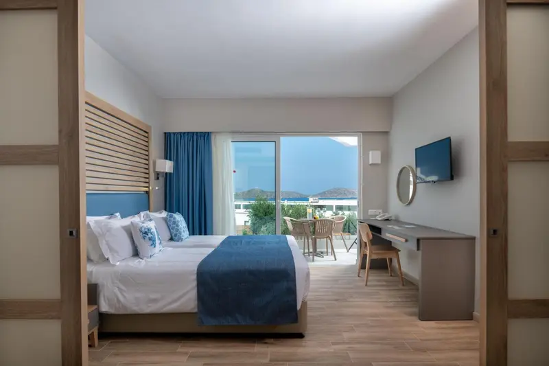 Chambre lumineuse avec un grand lit et une vue sur la mer.