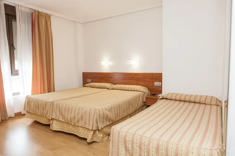 Chambre avec deux lits jumeaux et un lit simple.