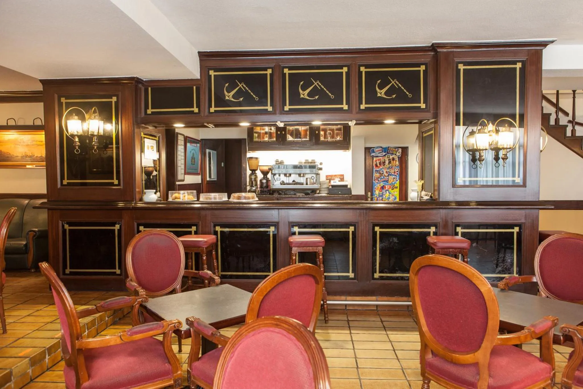 Un bar avec un comptoir en bois et des tabourets rouges.