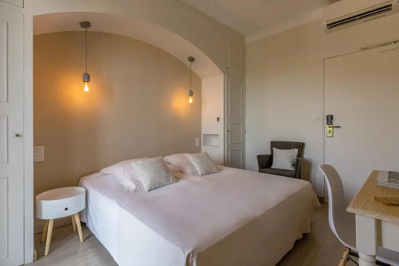 Une chambre lumineuse avec un lit double et un coin lecture.