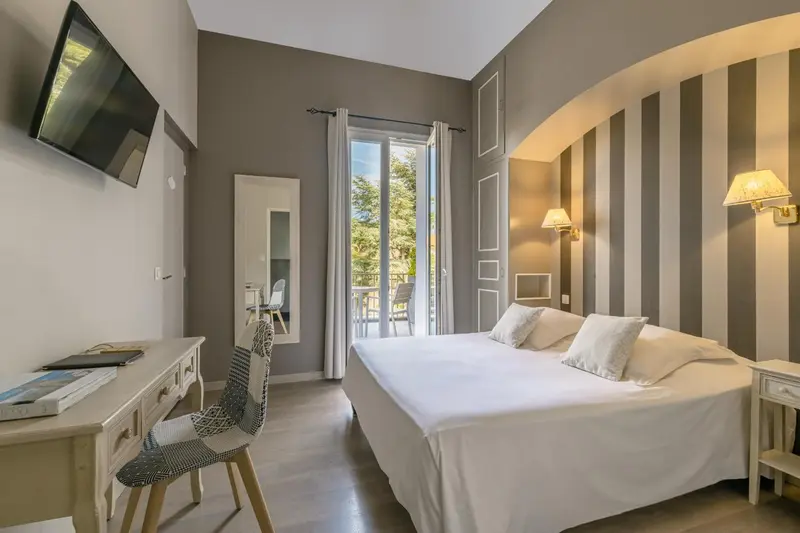 Une chambre lumineuse avec un lit blanc et un bureau.