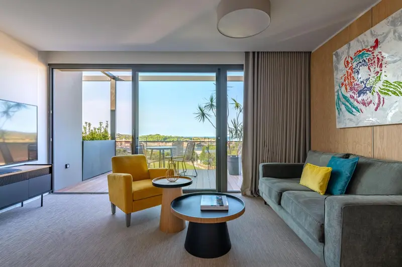 Un salon moderne s'ouvre sur une terrasse avec vue sur la végétation.