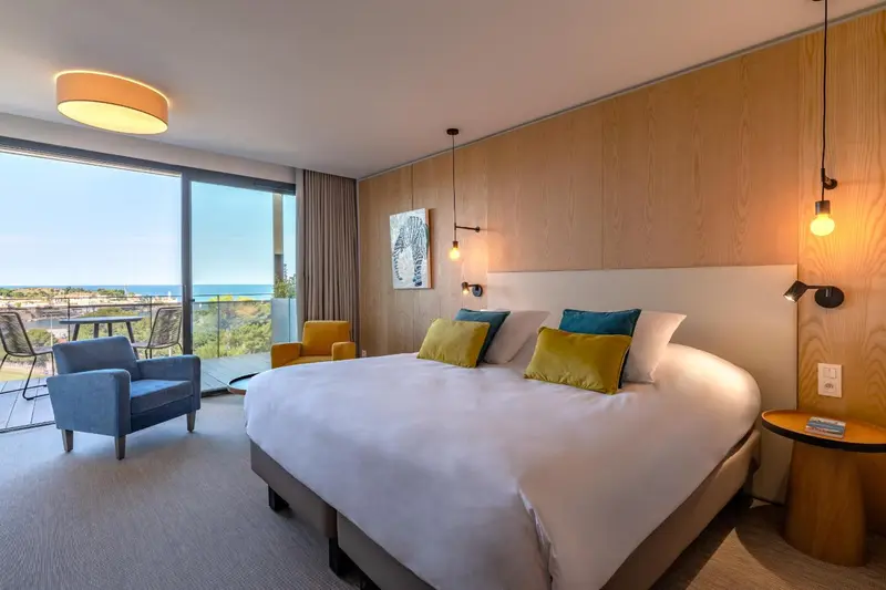 Chambre lumineuse avec un grand lit et vue sur la mer.