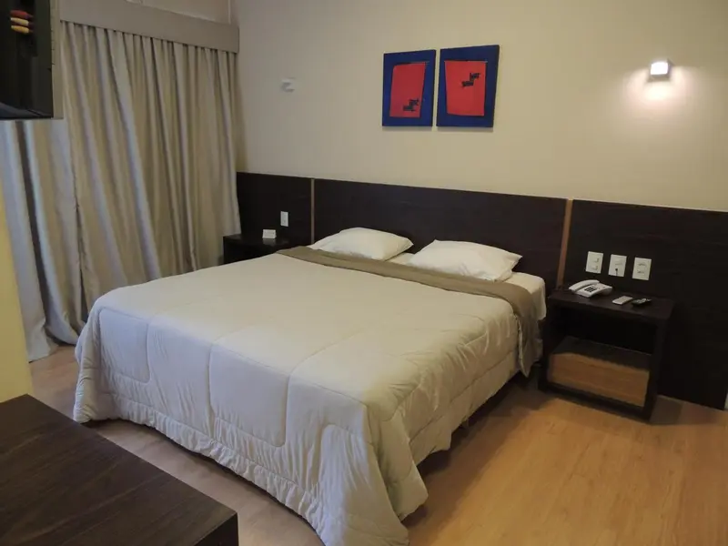 Une chambre avec un grand lit recouvert d'une couette blanche et de coussins.