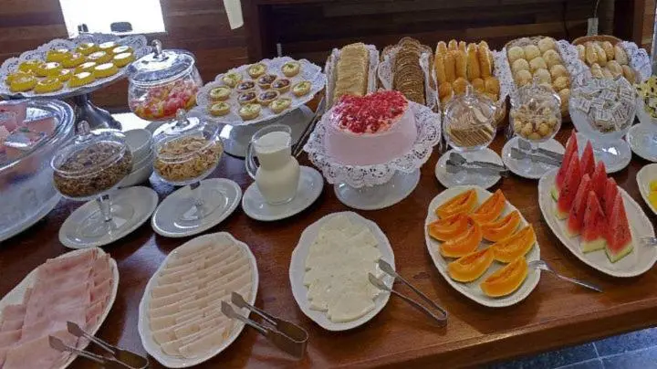 Une table garnie de pâtisseries, de fruits et de charcuteries est présentée en buffet.