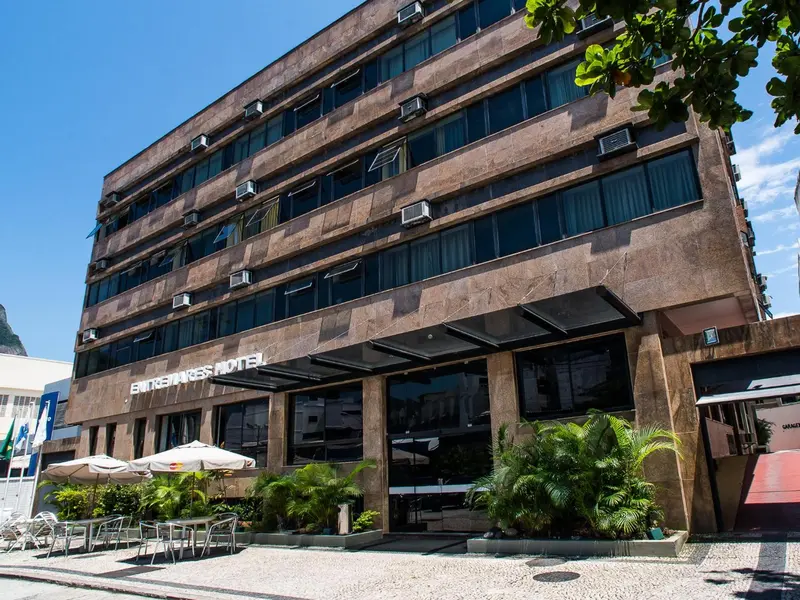 Facade d'un immeuble avec une entrée ombragée et des plantes.