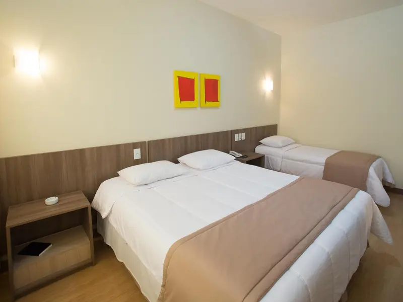 Une chambre lumineuse avec deux lits simples et des tables de chevet.