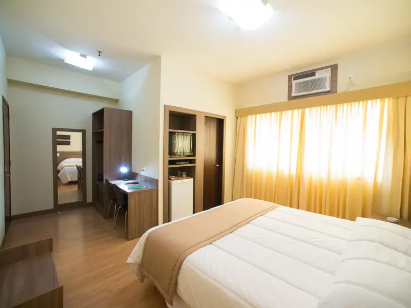 Une chambre lumineuse avec un grand lit et un bureau.