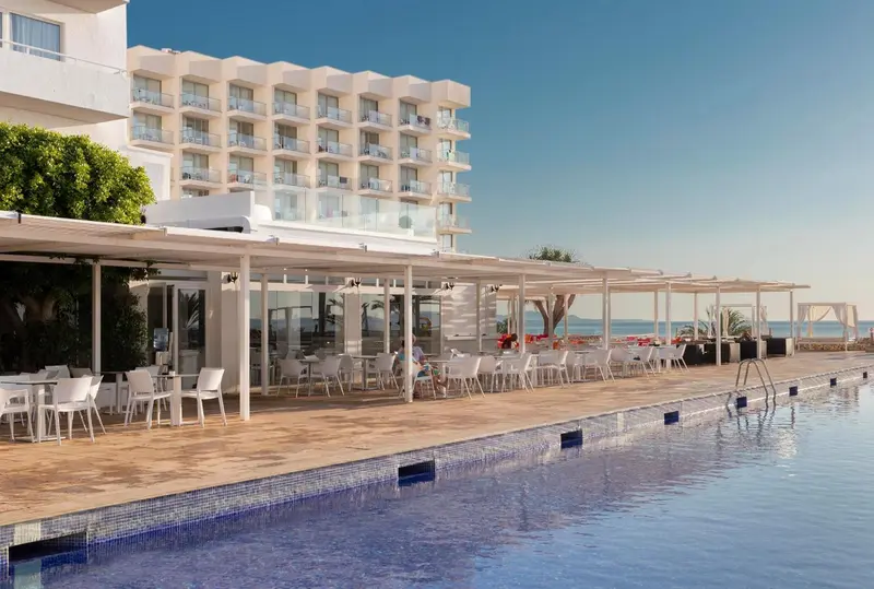 Terrasse ombragée avec tables et chaises près d'une piscine.