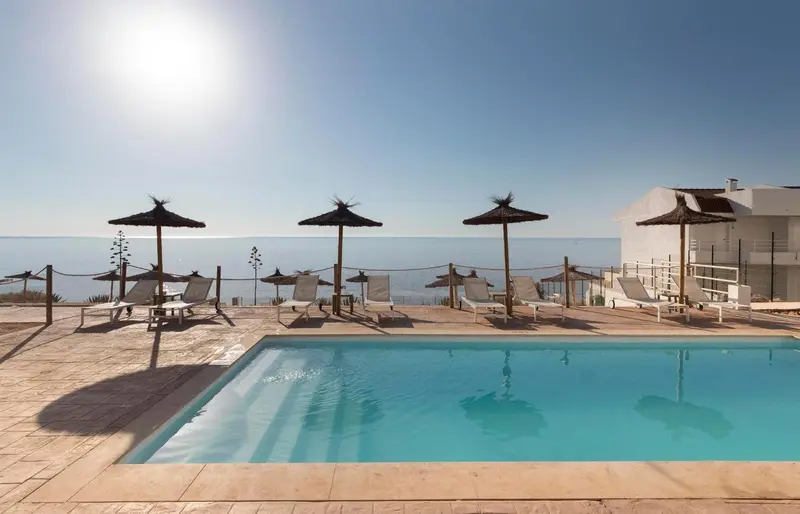 Terrasse avec piscine et chaises longues en bord de mer.