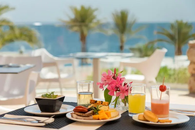 Une table est dressée avec des plats et des boissons, face à la mer.