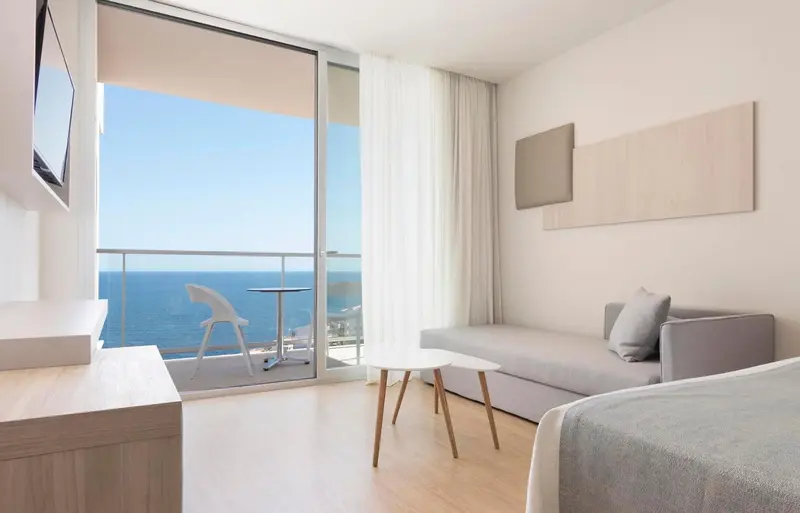 Espace de vie lumineux avec vue sur la mer depuis un balcon.