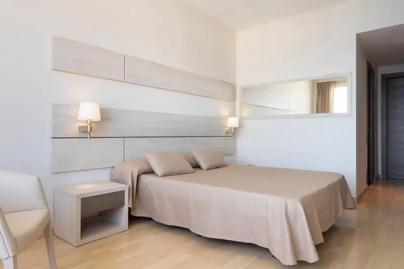 Une chambre lumineuse avec un grand lit et des tables de chevet.