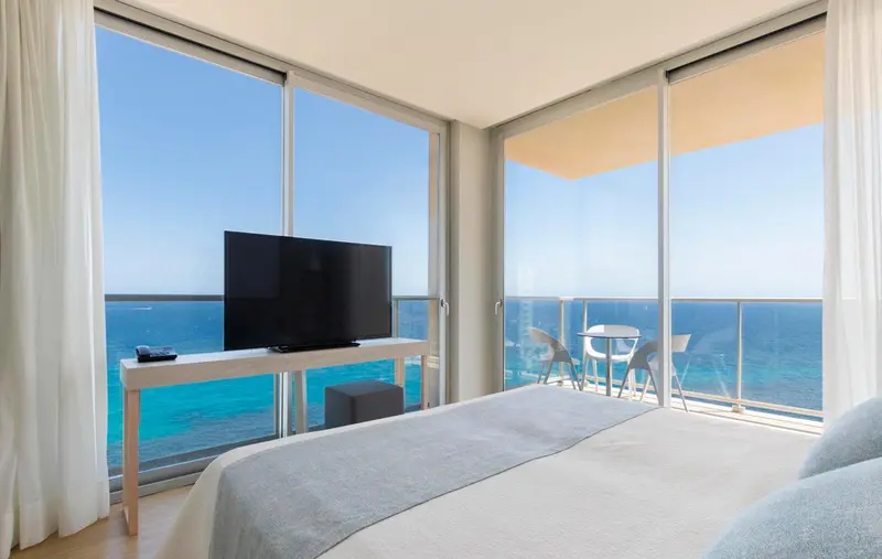 Une chambre lumineuse avec vue sur la mer depuis un balcon.