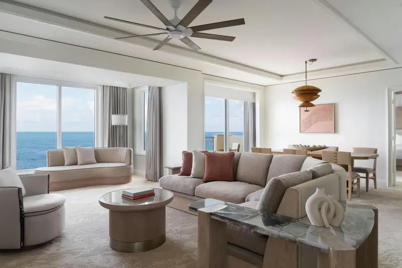 Un salon lumineux avec canapés et fauteuils face à une vue sur la mer.