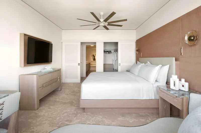 Une chambre lumineuse avec un grand lit et un téléviseur mural.