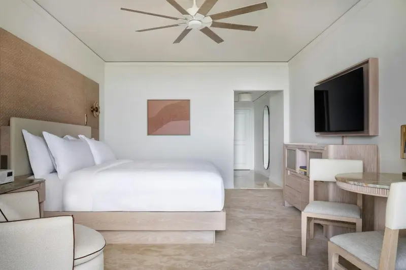 Une chambre lumineuse avec un grand lit et un espace bureau.